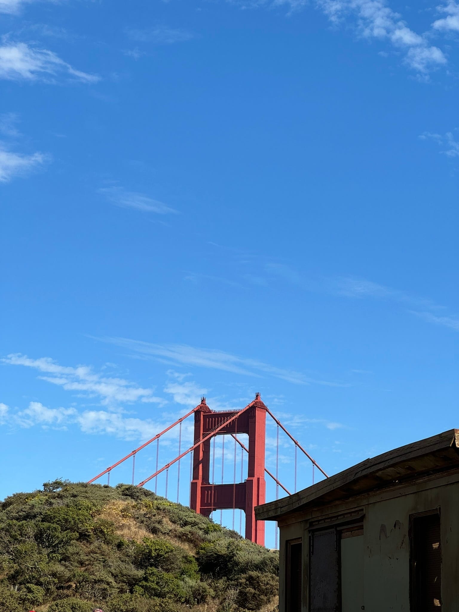 The Golden Gate Bridge rising behind a hill in San Francisco