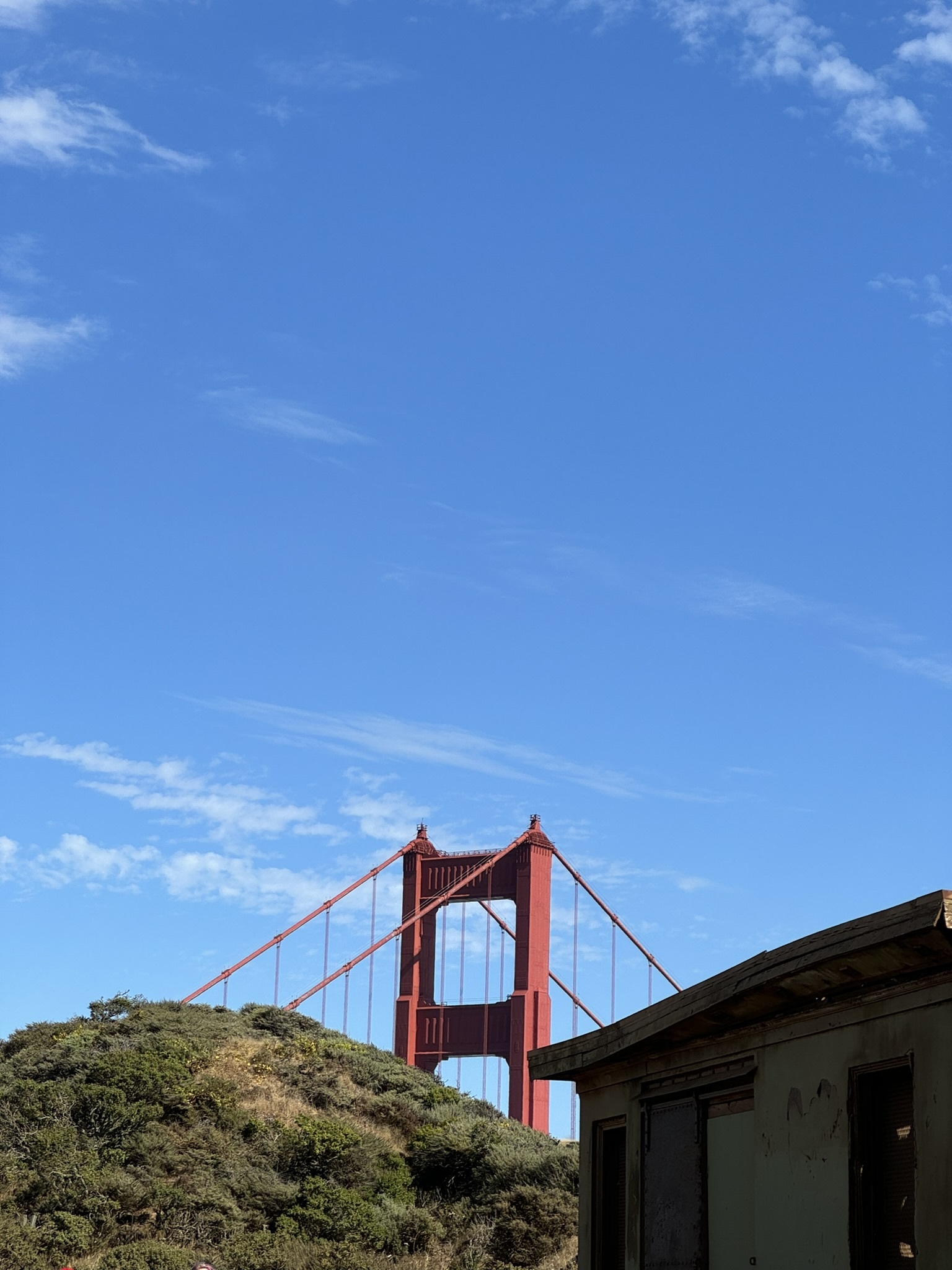 The Golden Gate Bridge rising behind a hill in San Francisco